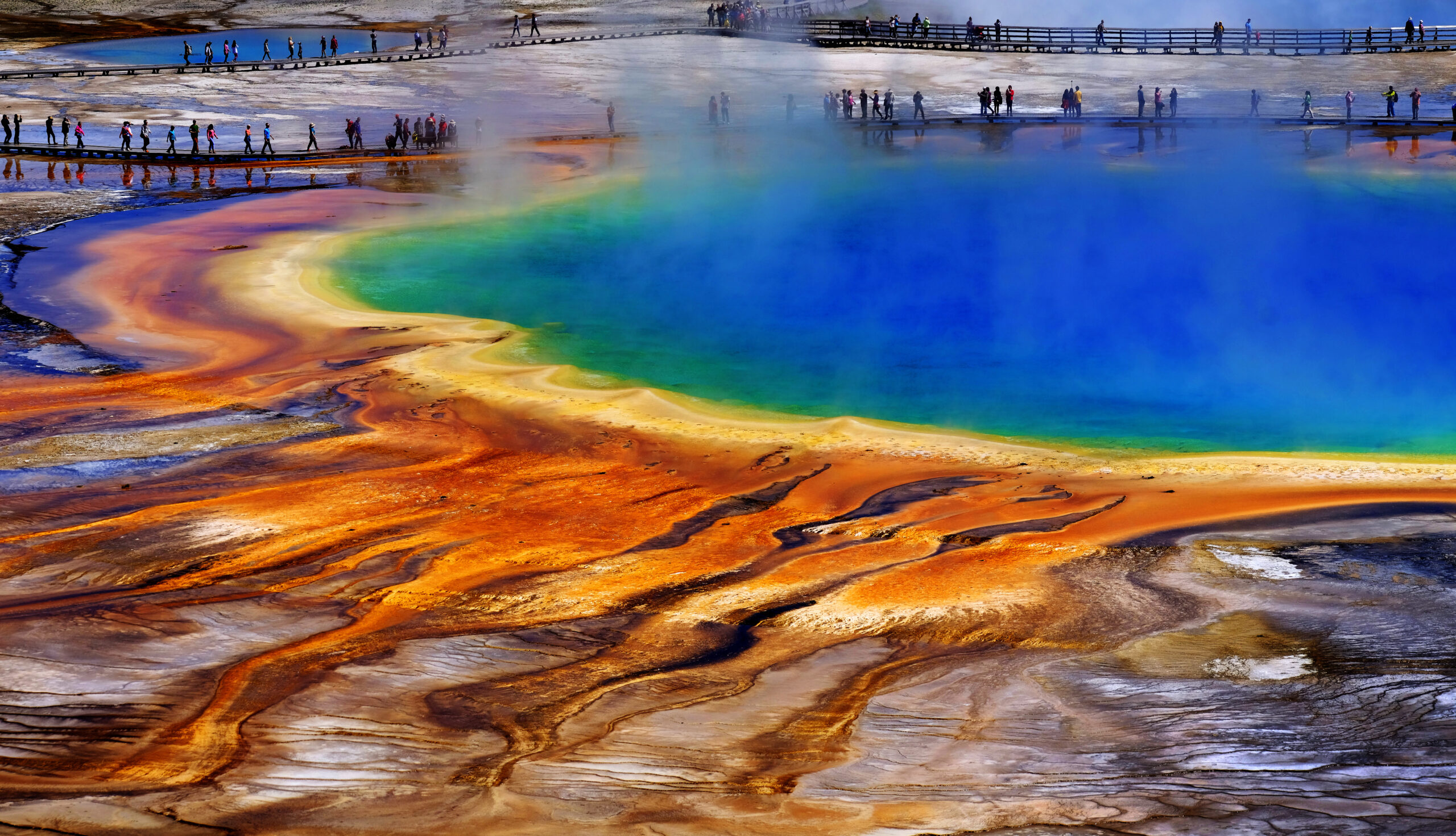 Grand Prismatice Spring in Yellowstone National Park with tourists viewing the spectacular natural scene